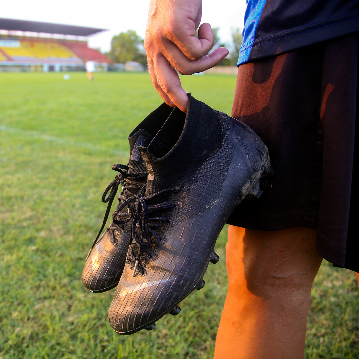 boy from the back holding a pair of cleats by the heel